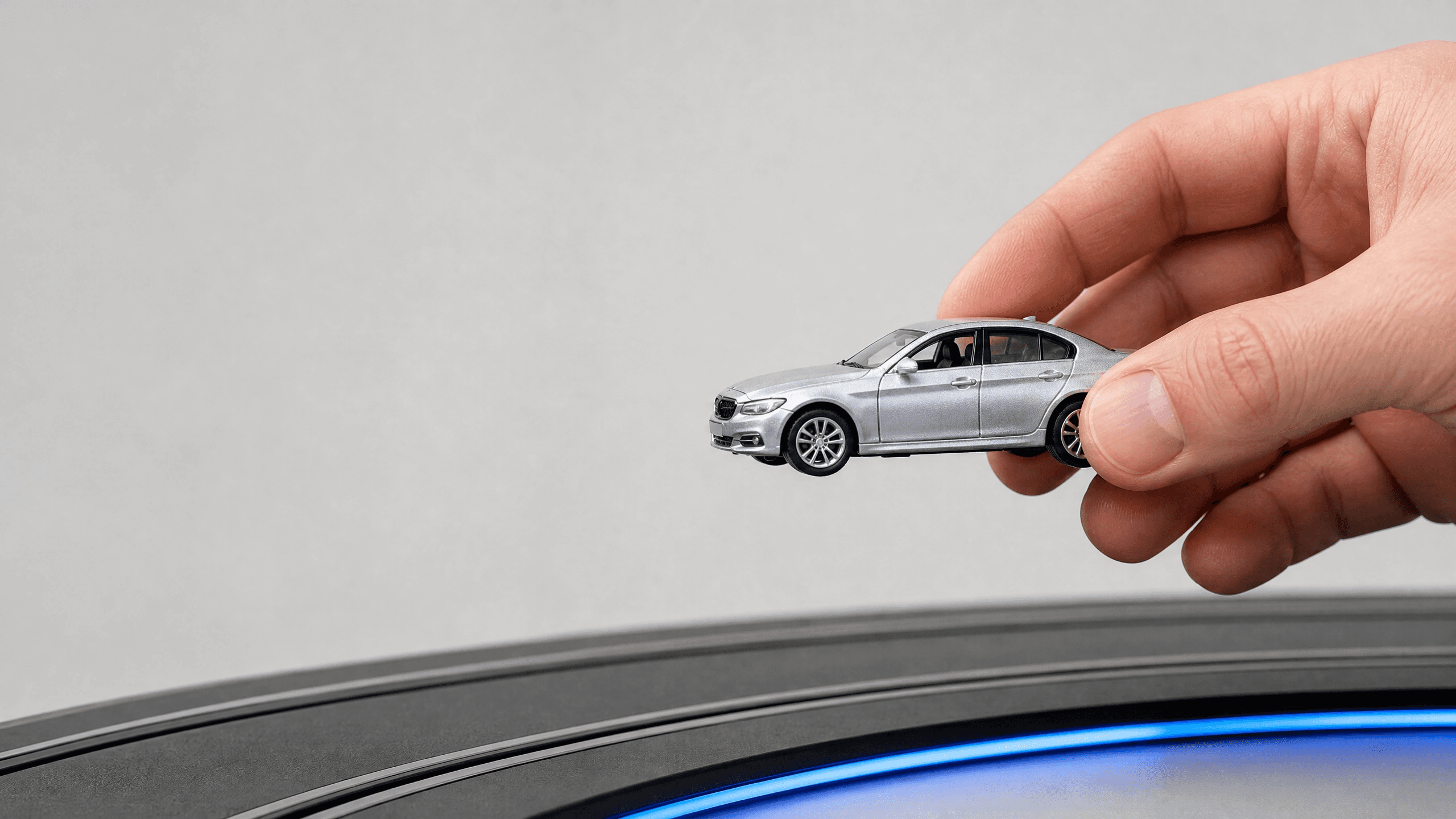 Mão comparando um carrinho diecast 1:64 com a largura de uma pista modular Vitrack